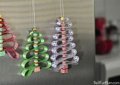 three christmas tree ornaments hanging from hooks on a refrigerator