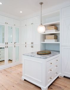 a kitchen with white cabinets and marble counter tops, along with an island in the middle