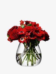 a vase filled with red flowers and greenery