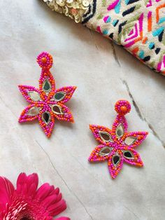 two pink flowers sitting on top of a table next to some beads and other items