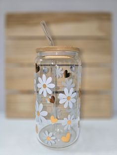 a glass jar with flowers painted on the side and a straw sticking out of it