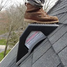 a man standing on top of a roof next to a pair of brown work boots