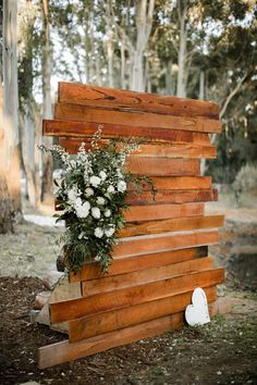 a wooden structure with flowers and greenery on the top is made out of wood planks