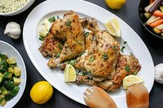 two chicken legs on a plate with lemons and vegetables