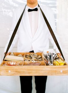 a man in a tuxedo is holding a tray with food and utensils