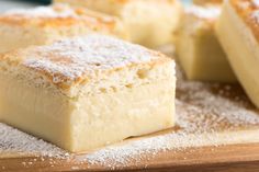 two pieces of cake sitting on top of a cutting board covered in powdered sugar