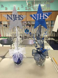 two glass vases with blue and silver stars on them sitting on a table in a classroom