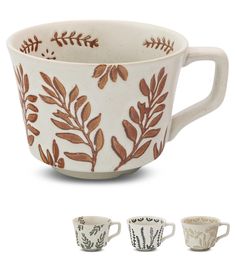 three coffee mugs with designs on them, one is white and the other has brown leaves