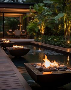 an outdoor fire pit in the middle of a pool at night with lit candles on it