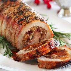 a meatloaf is cut into slices on a white plate with rosemary sprigs