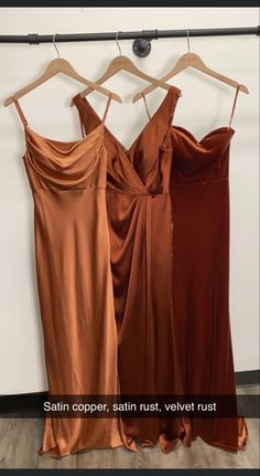 two dresses hanging on a rack in front of a wall with the words satin copper satin, velvet velvet rust