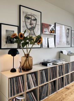 a record player sitting on top of a shelf next to a vase filled with sunflowers