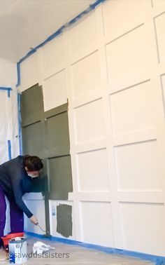 a woman is painting the walls of a room with green and white paint on it