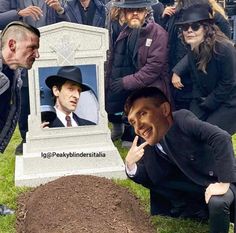 a group of people standing around a grave with a man's face on it