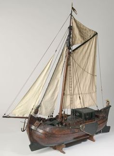 an old model sailboat with white sails