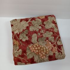 a red and gold floral design on a white background with some grapes in the center