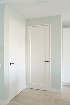 an empty room with two white doors and wood flooring on the side of the room