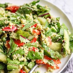 a white plate topped with cucumber and red pepper salad next to a fork