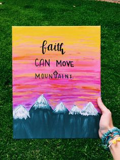 someone is holding up a sign that says faith can move mountains on the grass in front of them