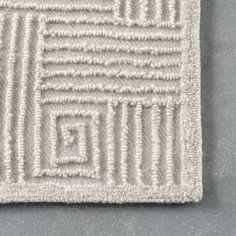 a close up of a white rug on a gray floor with an interesting design in the middle