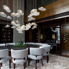 a dining room table with white chairs and lights hanging from it's centerpiece