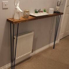 a table with some plants on it and a white vase sitting on top of it next to a radiator