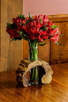 a vase filled with red flowers on top of a wooden table