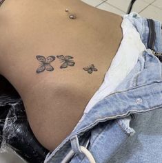 the back of a woman's stomach with three small butterflies on her left side