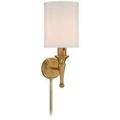 a wall light with a white shade on the side and a gold finish to it