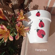 a white cup with ladybugs painted on it next to a pink flower pot