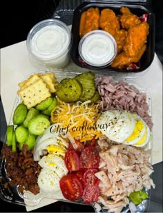 a tray filled with different types of food next to two containers of dip sauces