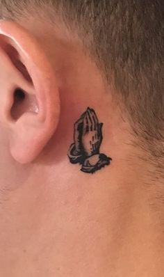 a man with a small tattoo on his neck and behind the ear is a praying hand