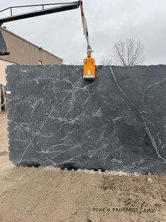 a large granite slab being lifted by a crane