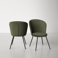 two green chairs sitting next to each other on top of a cement floor with white walls in the background