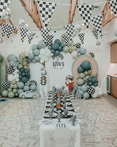 a table set up for a race themed birthday party with balloons and checkered flags