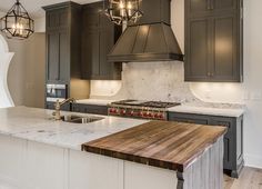 a large kitchen with an island counter top and two pendant lights hanging from the ceiling