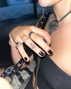 a woman with two rings on her fingers and a star tattoo on her left hand