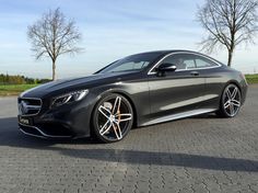 the mercedes s - class coupe is parked in a parking lot with trees behind it