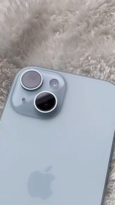 an iphone is laying on a fluffy white blanket with the camera lens cover open and showing