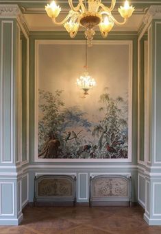 an empty room with paintings on the wall and chandelier