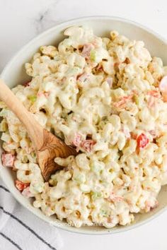 a bowl full of macaroni salad with a wooden spoon