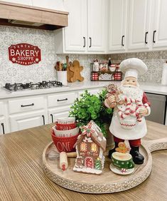 a santa clause figurine sitting on top of a wooden tray in a kitchen