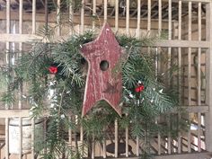 a birdhouse is decorated with pine branches and holly wreaths for the holiday season