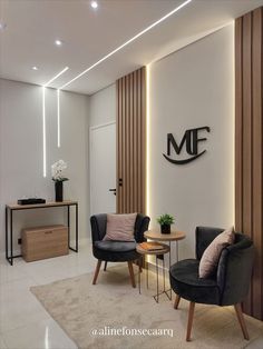 a living room with two chairs and a table in front of a wall that has the mf logo on it