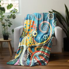 an octopus blanket sitting on top of a couch next to a potted plant