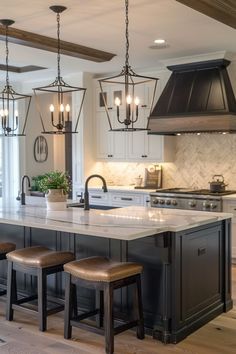 a large kitchen island with stools in front of it and lights hanging from the ceiling