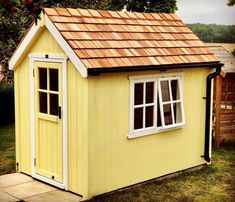 a small yellow shed with a brown roof