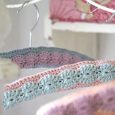 two crocheted bedspreads hanging from hooks in a room with pink and white walls