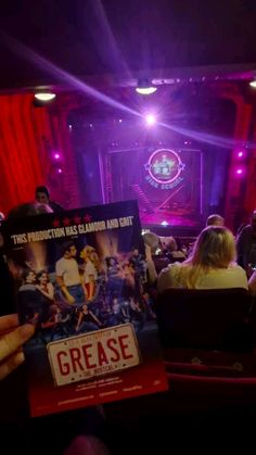 a person holding up a movie poster in front of a group of people sitting down