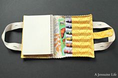 an open notebook with some crayons on it and a notepad inside the book